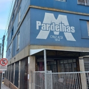 Vê-se um prédio azul de quatro andares com a logo da escola pintado na parede.
